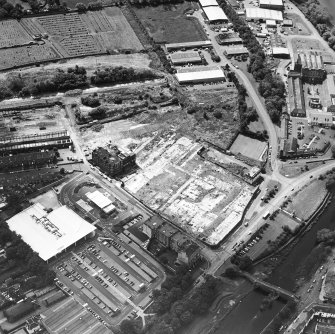 Oblique aerial view centred on the remains of the works with church and burial ground adjacent, taken from the NNE.