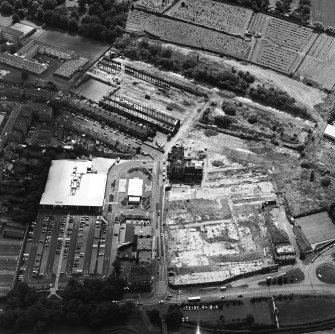 Oblique aerial view centred on the remains of the works with church and burial ground adjacent, taken from the NW.