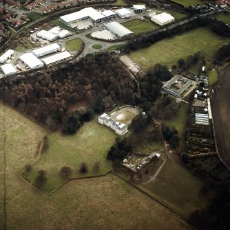 Oblique aerial view centred on the country house with walled garden, stables, cottage, formal garden, gate lodge and dovecot adjacent, taken from the NNE.