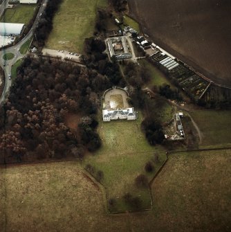 Oblique aerial view centred on the country house with walled garden, stables, cottage, formal garden, gate lodge and dovecot adjacent, taken from the NE.