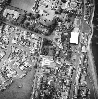Oblique aerial view centred on the house and stables with the church adjacent, taken from the NE.