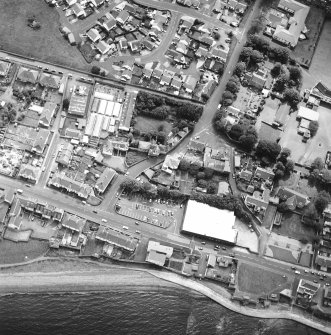 Oblique aerial view centred on the house and stables with the church adjacent, taken from the NW.