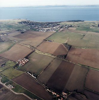 General oblique aerial view looking across the modern amalgamated fields, farmhouse, farmsteading and village towards the Firth of Forth and the Lomond Hills beyond, taken from the ESE.