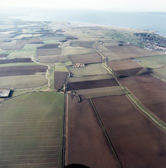 General oblique aerial view looking across the modern amalgamated fields, farmhouse, farmsteading and village towards the golf course and the Firth of Forth, taken from the ENE.