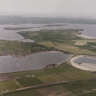 Oblique aerial view from SSE, centred on the island of Burray and showing Burray Village in the centre left of the photograph, and Churchill Barrier No. 4 in the right centre. N Cara Mound is visible in the bottom left-hand corner.