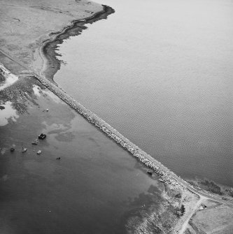 Oblique aerial view from E, centred on the Barrier, and showing the wreck of the blockship Elton in the centre left of the photograph, and traces of Air-raid Shelters and a Tramway on Glimps Holm in the top left-hand corner.