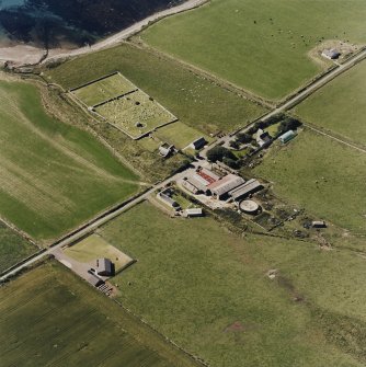 Oblique aerial view of Orphir, St Nicholas's Church, burial-ground and the Earl's Bu with mill, taken from the NE. Also visible is the Bu of Orphir farmhouse and farmsteading.