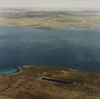 Oblique aerial view of Scad Head, general view over the Bring Deeps looking to mainland Orkney, of Second World War coastal battery, gun emplacements, observation post and searchlight positions, taken from the SW.  Also visible is the tramway connecting the public road to the battery.