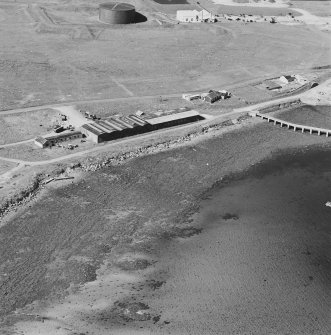 Oblique aerial view of Orkney, Hoy, Lyness, Royal Naval Oil Terminal, view from S, of the former recreation centre and NAAFI.  Part of the former boiler house, now the museum with the remaining oil tank is visible in the background.