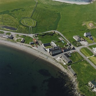 Oblique aerial view of the village with the burial ground adjacent, taken from the E.