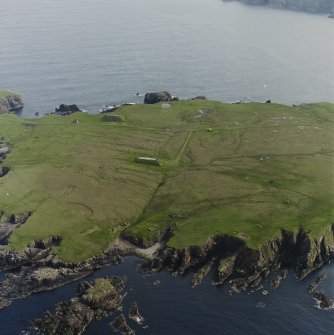 Oblique aerial view centred on the remains of the radar station, engine house, structures and enclosure, taken from the NNW.