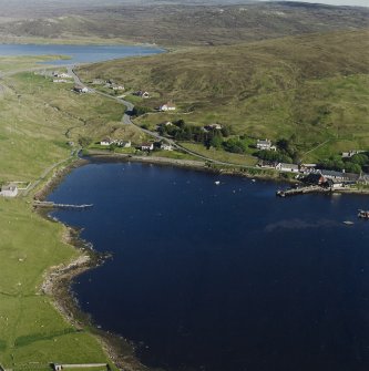 Oblique aerial view looking across Olna Firth to the village of Voe, the fish processing plant and the pier, taken from the NW.