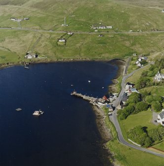 Oblique aerial view looking across Olna Firth to the village of Voe, the fish processing plant and the pier, taken from the WSW.