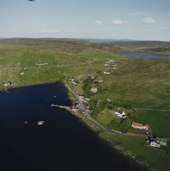 General oblique aerial view looking across Olna Firth to the village of Voe, the fish processing plant and the pier, taken from the WSW.