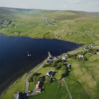 General oblique aerial view looking across Olna Firth to the village of Voe, the fish processing plant and the pier, taken from the SSW.