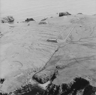 Oblique aerial view centred on the remains of the radar station, engine house, structures and enclosure, taken from the N.