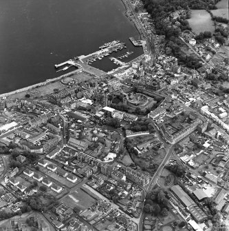 Oblique aerial view of Rothesay, taken from the SW, centred on the town.  The harbour is visible in the top right side of the photograph.   The castle and the Winter Gardens are visible in the centre of the photograph.