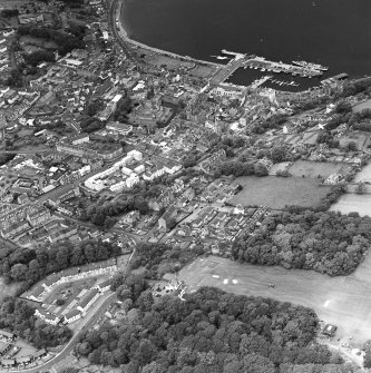 Oblique aerial view of Rothesay, taken from the S, centred on the town.  A harbour is visible in top right-hand side of the photograph.  A castle and the Winter Gardens are visible in the top centre of the photograph.