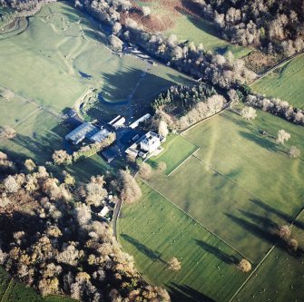 Oblique aerial view centred on the country house, walled garden and farmstead with the remains of the cairn adjacent, taken from the W.