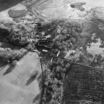 Oblique aerial view centred on the farmstead with the castle adjacent, taken from the N.