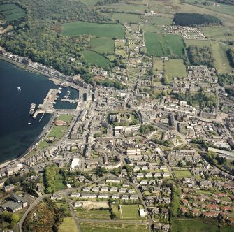 General oblique aerial view of Rothesay centred on the remains of the castle and chapel, with the winter gardens and pier adjacent taken from the W.