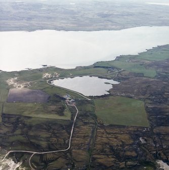 General oblique aerial view centred on the farmhouse, farmsteading and crannog with lazy beds adjacent, taken from the NW.