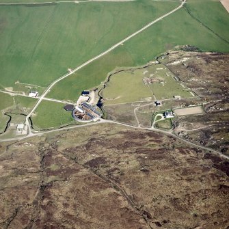 Oblique aerial view centred on the farmhouse, farmsteading, engine house and hut, taken from the SE.