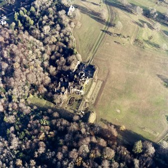 Oblique aerial view centred on the remains of the country house with the church adjacent, taken from the WSW.