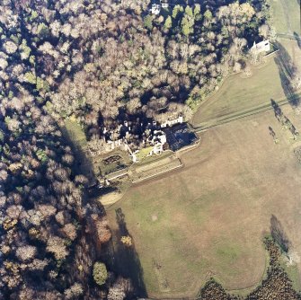 Oblique aerial view centred on the remains of the country house with the church adjacent, taken from the SSW.