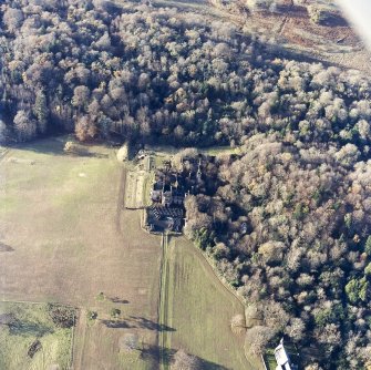Oblique aerial view centred on the remains of the country house with the church adjacent, taken from the ESE.