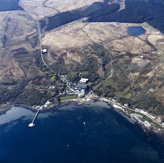 Oblique aerial view centred on the distillery, hotel and piers, taken from the NE.