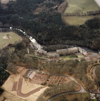 Oblique aerial view of New Lanark centred on the mills and schools, taken from the NE.