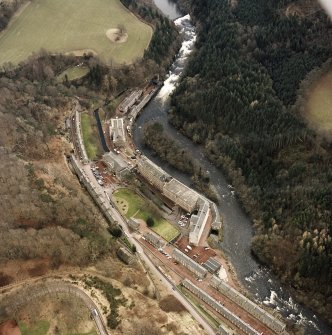 Oblique aerial view of New Lanark centred on the mills and schools, taken from the NNW.