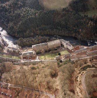 Oblique aerial view of New Lanark centred on the mills and schools, taken from the NE.