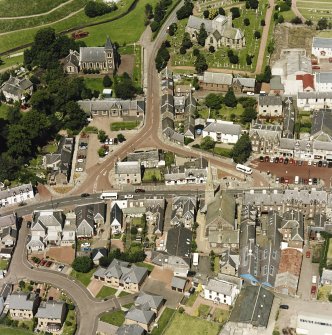 Oblique aerial view of Biggar centred on Biggar Church, churchyard, Moat Park Church and church hall, taken from the SE.