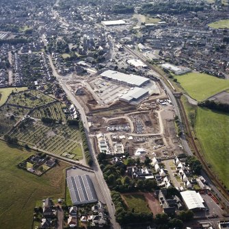 Oblique aerial view centred on the site of the market, the shopping centre and new housing, taken from the SE.