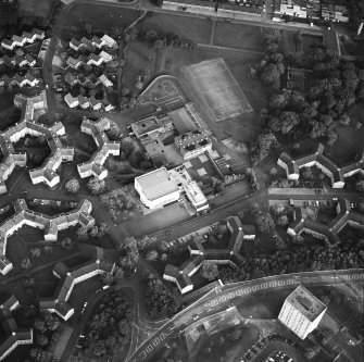 Oblique aerial view of Cumbernauld centred on sacred Heart Roman Catholic Church with the Sacred Heart Roman Catholic Primary School adjacent, taken from the NW and recorded as part of the World of Worship project.