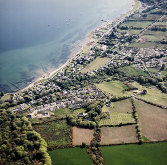 General oblique aerial view centred on the village of Lamlash, the chapel and burial-ground, taken from the NNE.