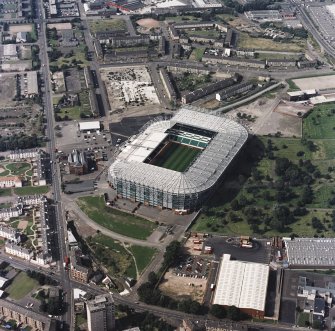 Oblique aerial view, taken from the E.
Centred on Celtic Park football stadium, and showing the Eastern Necropolis graveyard in the centre right of the photograph.