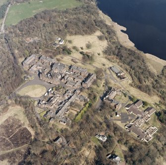 Oblique aerial view centred on the hospital, halls, nurses home, former mortuary, and workshops, taken from the WSW.