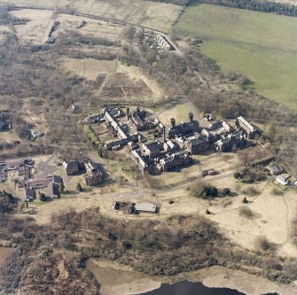 Oblique aerial view centred on the hospital, halls, nurses home, former mortuary, and workshops, taken from the SE.