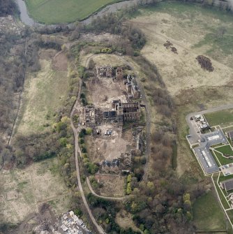 Oblique aerial view centred on the hospital partly under demolition, taken from the SE.