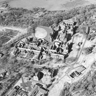 Oblique aerial view centred on the hospital, halls, nurses home, former mortuary, and workshops, taken from the SSW.