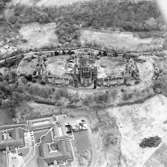 Oblique aerial view centred on the hospital partly under demolition, taken from the NE.