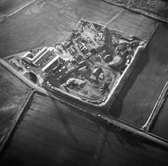 Oblique aerial view centred on the works and the remains of the field boundary, taken from the NE.