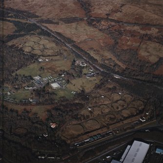 Oblique aerial view centred on the military training camp and farmsteading with oil fuel depots and building adjacent, taken from the SSW.