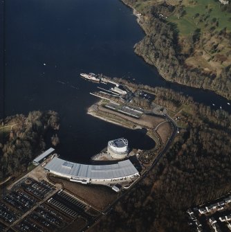 Oblique aerial view centred on the shopping centre and visitor centre with the pier and slipway adjacent, taken from the SSW.
