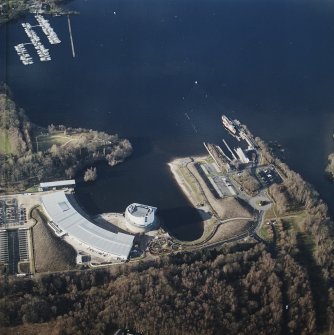Oblique aerial view centred on the shopping centre and visitor centre with the pier and slipway adjacent, taken from the SE.