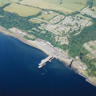Oblique aerial view centred on the railway terminus, pier, farmsteading and the site of the country house, taken from the SW.