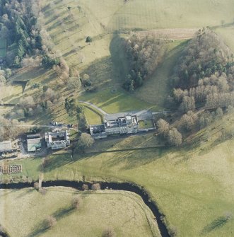 Oblique aerial view centred on the country house with stables and bridge adjacent, taken from the N.